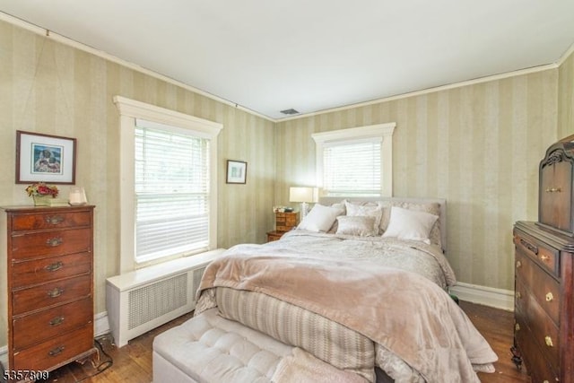 bedroom featuring wood finished floors, multiple windows, radiator, wallpapered walls, and ornamental molding