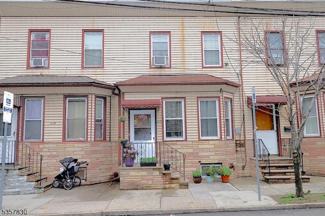 townhome / multi-family property with stone siding and cooling unit