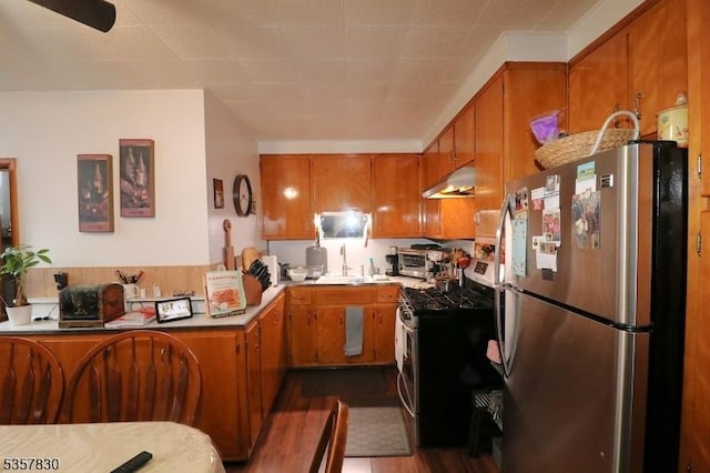 kitchen with appliances with stainless steel finishes, under cabinet range hood, brown cabinets, and a sink