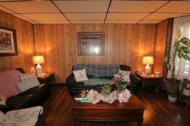 living area with a drop ceiling, wood finished floors, and wood walls