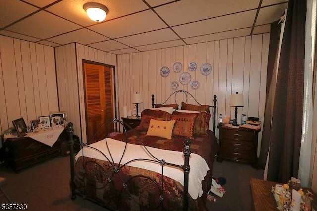 bedroom with a paneled ceiling, carpet flooring, and a closet