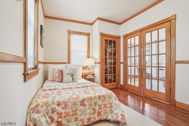 bedroom with french doors, crown molding, and wood finished floors