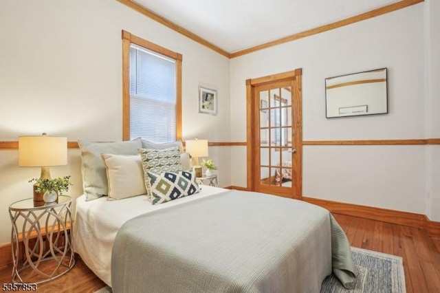 bedroom with wood finished floors, baseboards, and ornamental molding