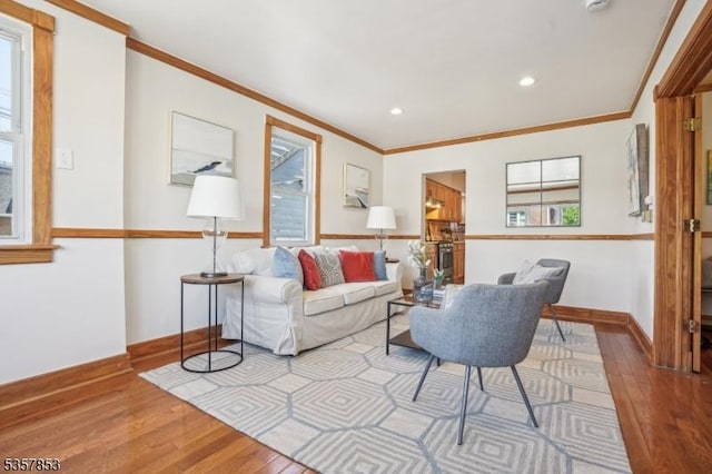 living area with wood-type flooring, ornamental molding, baseboards, and recessed lighting