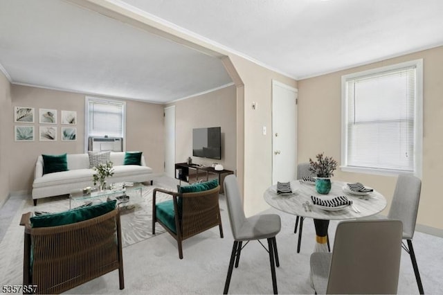 carpeted living area with arched walkways, ornamental molding, and baseboards