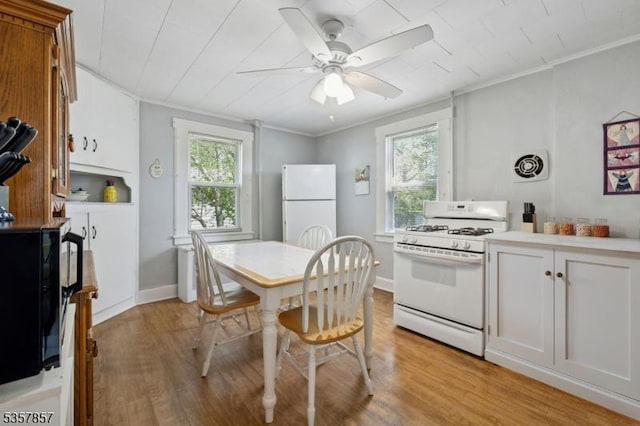 kitchen featuring white appliances, light wood-style floors, a ceiling fan, crown molding, and light countertops