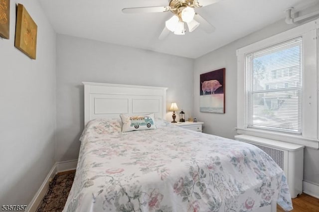bedroom with baseboards, radiator, ceiling fan, and wood finished floors