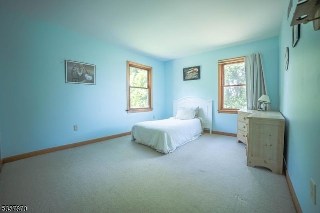 bedroom featuring light colored carpet and baseboards