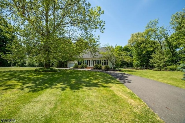 view of front of property featuring asphalt driveway, a front yard, and a garage