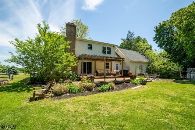rear view of property with a wooden deck, a pergola, a lawn, and a chimney