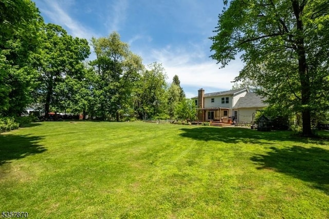 view of grassy yard with a wooden deck