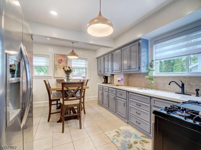kitchen with stainless steel fridge, gray cabinetry, black gas range, light countertops, and baseboards