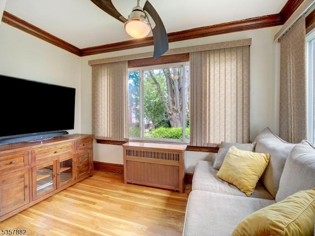 living area featuring radiator heating unit, crown molding, baseboards, and light wood-style flooring