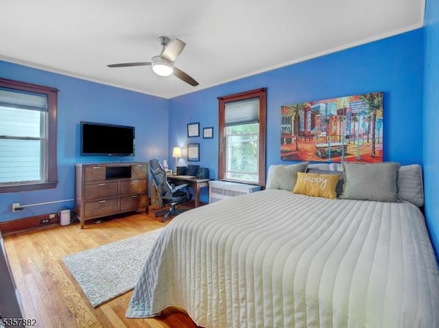 bedroom featuring wood finished floors, radiator, and ceiling fan
