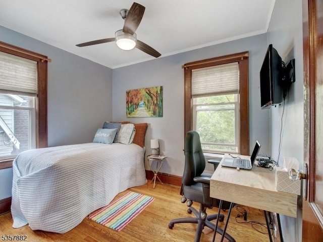 bedroom with light wood-style floors, a desk, ornamental molding, baseboards, and ceiling fan