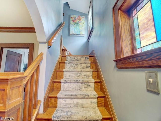 stairs featuring baseboards, wood finished floors, and arched walkways