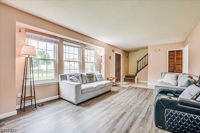 living room featuring wood finished floors, baseboards, and stairway