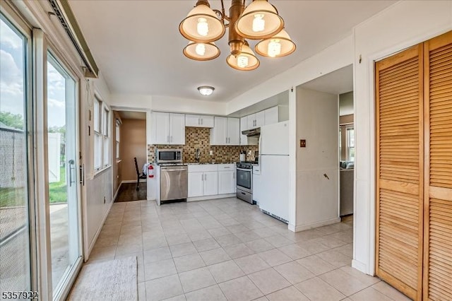 kitchen featuring stainless steel appliances, light tile patterned floors, a chandelier, decorative backsplash, and white cabinetry