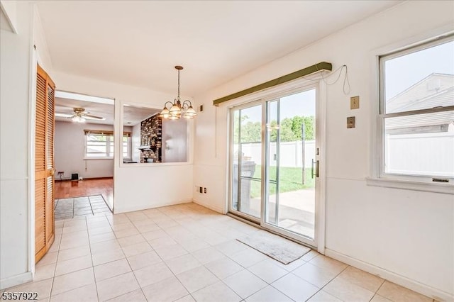 unfurnished dining area featuring a chandelier, light tile patterned floors, and baseboards