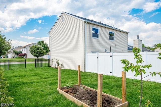 view of property exterior with a vegetable garden and a gate
