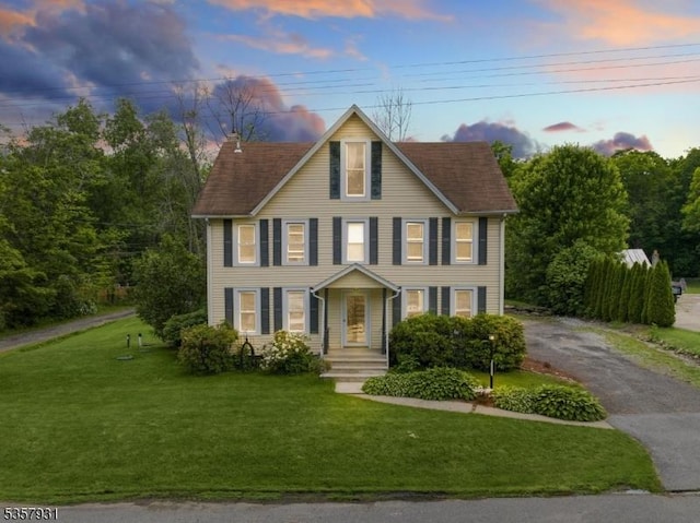 view of front of home with driveway, a lawn, and a chimney