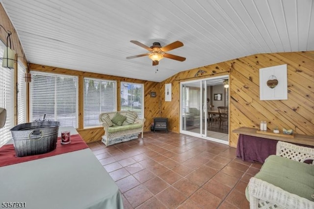 tiled living area featuring ceiling fan and wooden walls