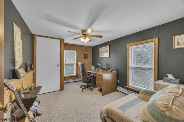 carpeted home office with healthy amount of natural light, a ceiling fan, wooden walls, and baseboard heating