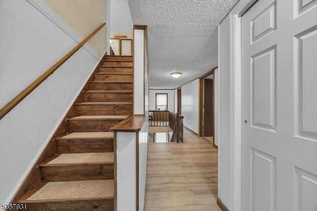 stairs featuring wood finished floors and a textured ceiling