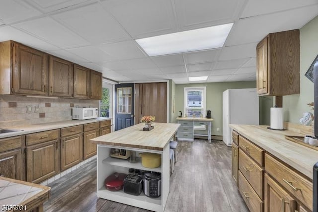 kitchen featuring wooden counters, white microwave, open shelves, dark wood-style flooring, and plenty of natural light