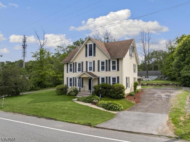 view of front of property featuring asphalt driveway and a front lawn