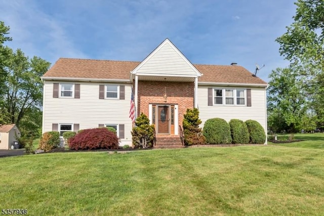 raised ranch with a front yard and brick siding