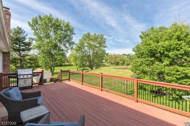 deck with a lawn, a grill, and view of wooded area