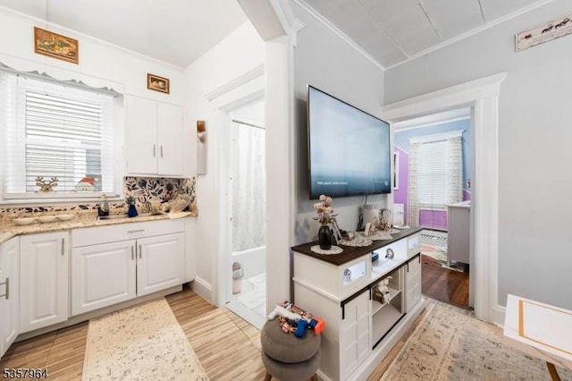 kitchen featuring light wood finished floors, white cabinets, light stone counters, and decorative backsplash