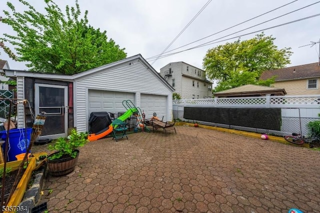view of patio / terrace featuring fence, a garage, and an outbuilding