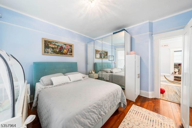 bedroom with dark wood-style floors, a closet, and baseboards