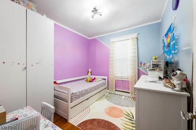 bedroom with crown molding and wood finished floors