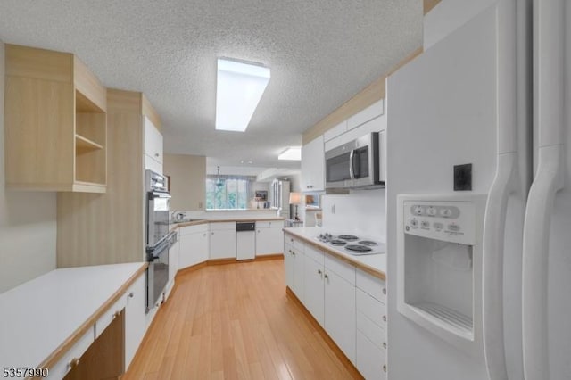 kitchen with white appliances, a textured ceiling, light wood-type flooring, light countertops, and white cabinets