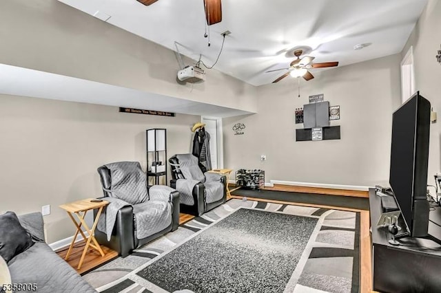 living room with ceiling fan, baseboards, and wood finished floors