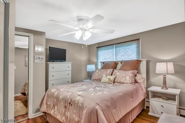bedroom featuring wood finished floors, ceiling fan, and a baseboard radiator