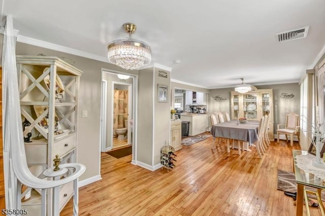 dining area featuring light wood-style floors, a chandelier, crown molding, and baseboards