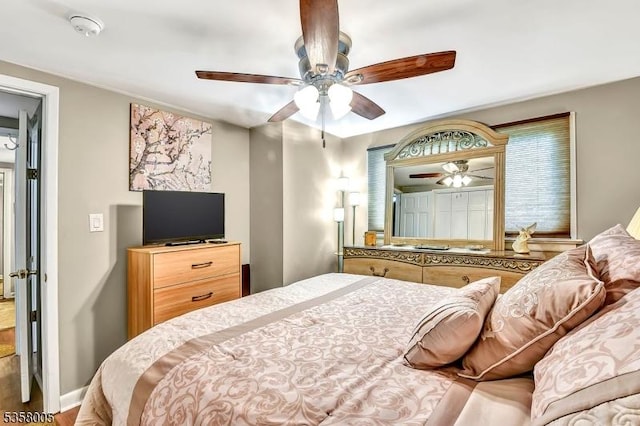 bedroom featuring ceiling fan, wood finished floors, multiple windows, and baseboards