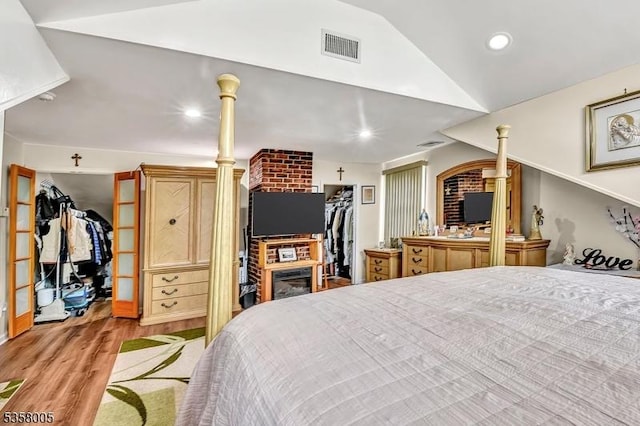 bedroom with a spacious closet, a closet, wood finished floors, lofted ceiling, and recessed lighting