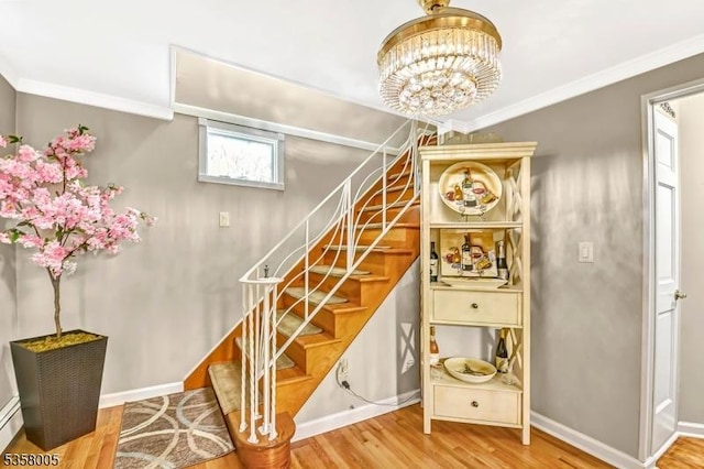 stairway featuring wood finished floors, ornamental molding, a chandelier, baseboards, and a baseboard heating unit