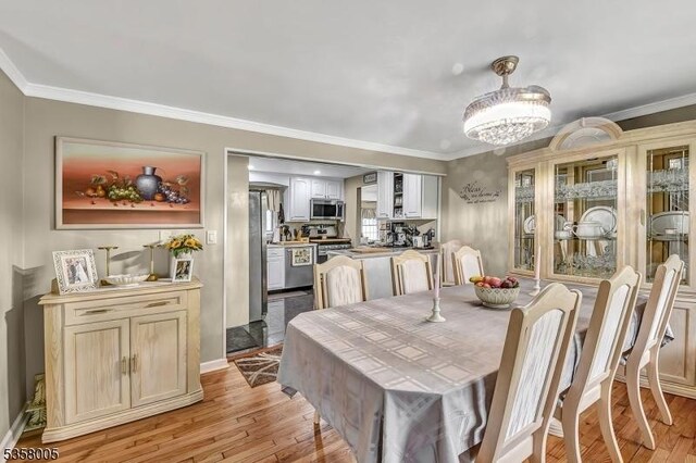 dining room with light wood-type flooring, a chandelier, and ornamental molding