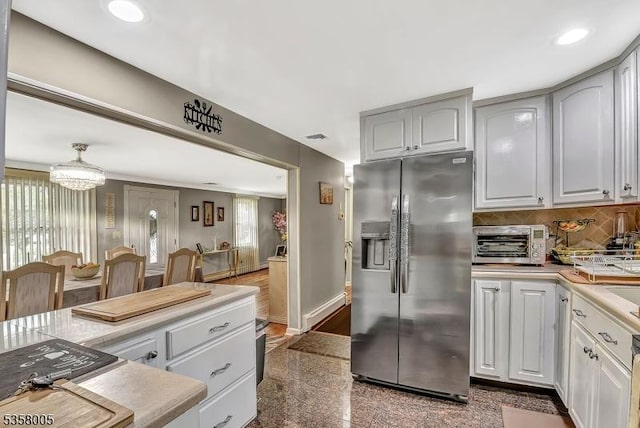 kitchen featuring stainless steel fridge, granite floors, decorative backsplash, recessed lighting, and light countertops