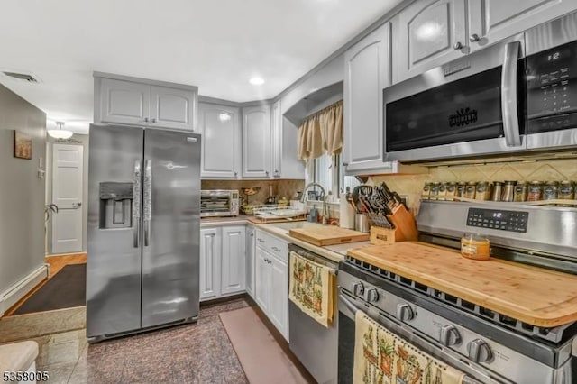 kitchen featuring appliances with stainless steel finishes, tasteful backsplash, a sink, recessed lighting, and granite tiled floors
