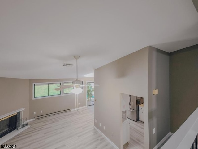 hallway featuring a baseboard heating unit, light wood-style flooring, and baseboards