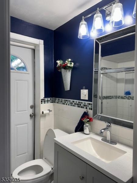 64 Dater St, North Haledon Boro, NJ 07508 - bathroom with tile walls, vanity, toilet, a stall shower, and backsplash