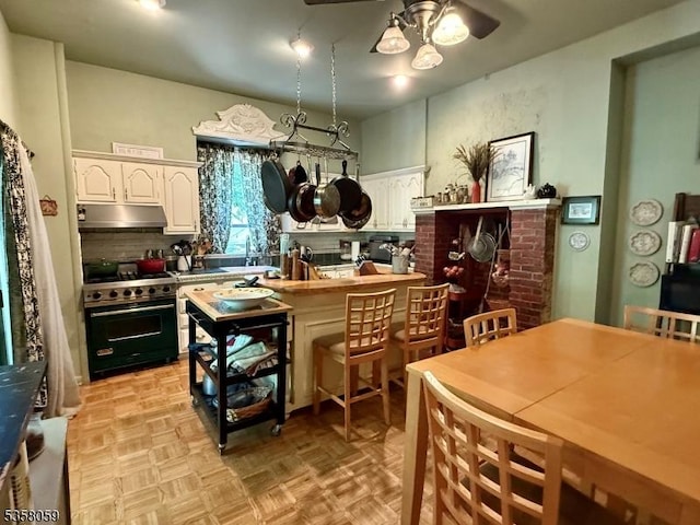 208 Rockaway St, Boonton Town, NJ 07005 - kitchen featuring range with gas stovetop, under cabinet range hood, a ceiling fan, white cabinetry, and backsplash