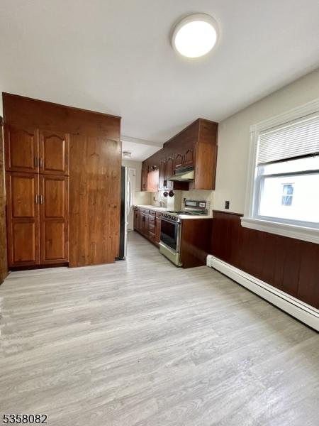277 Watchung Ave, North Plainfield Boro, NJ 07060 - kitchen featuring stainless steel range, under cabinet range hood, light wood-style flooring, baseboard heating, and light countertops